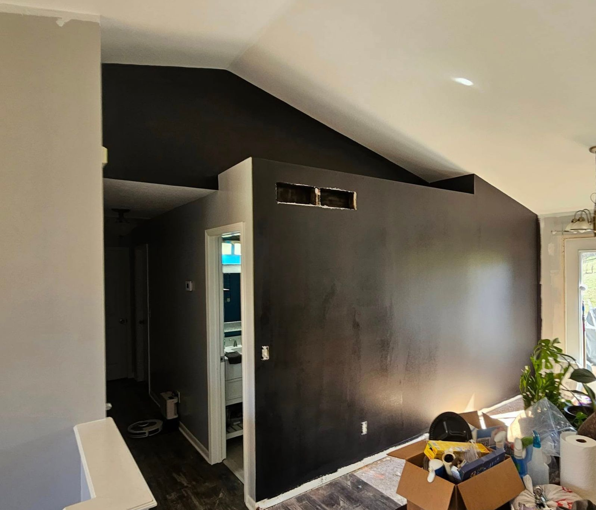 Partially renovated room with a dark accent wall, open doorway, and boxes on the floor