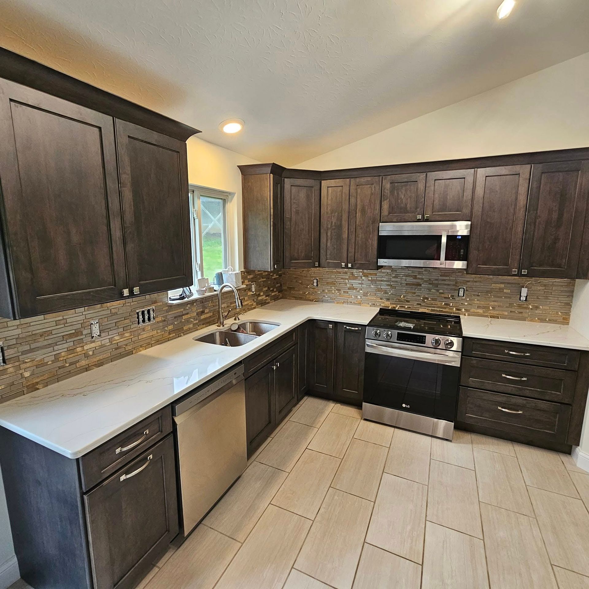 Modern kitchen with dark wood cabinets, stainless appliances, and light tile floor