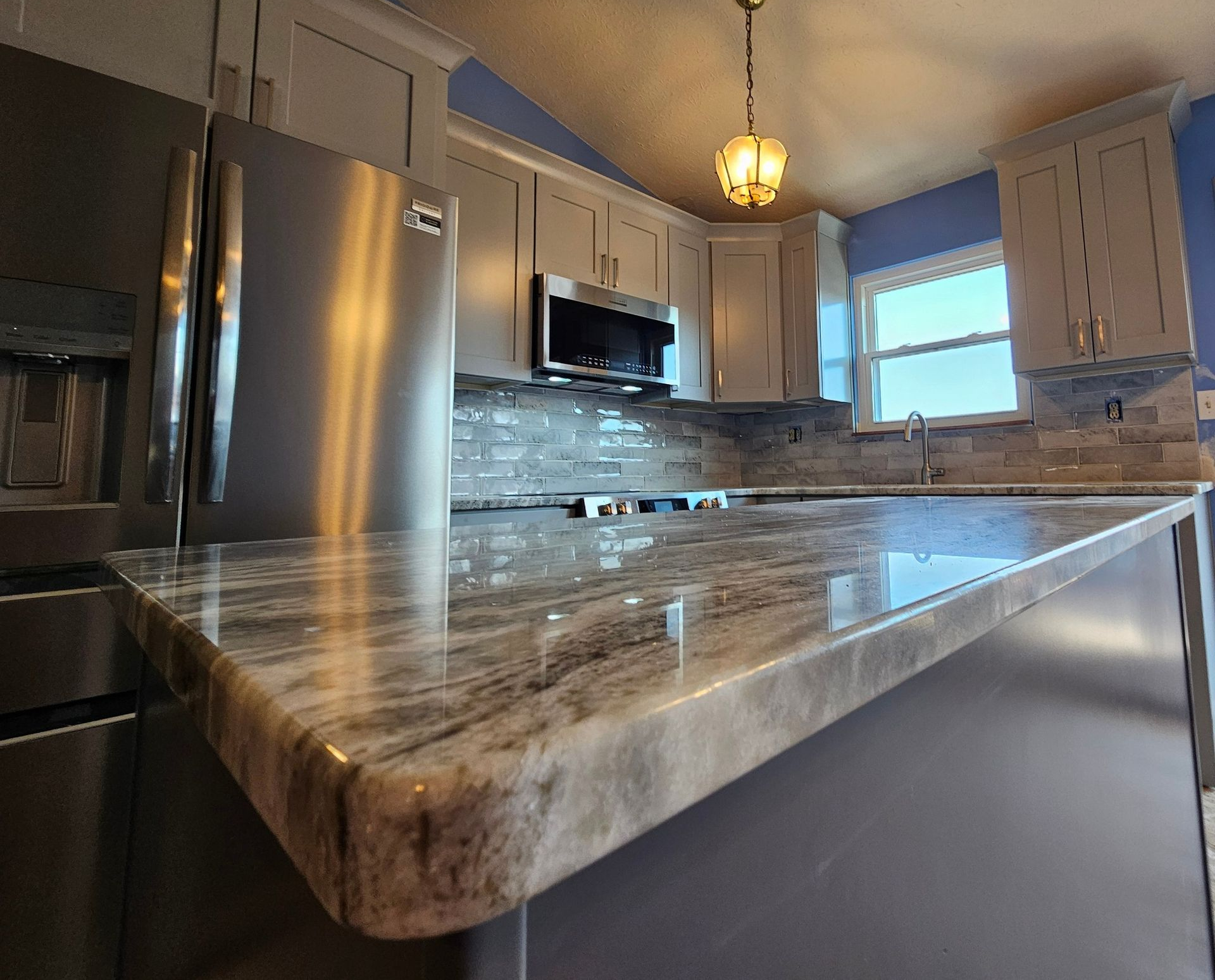 Modern kitchen with stainless steel appliances and a marble-look island countertop
