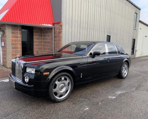 A black rolls royce parked in front of a building.