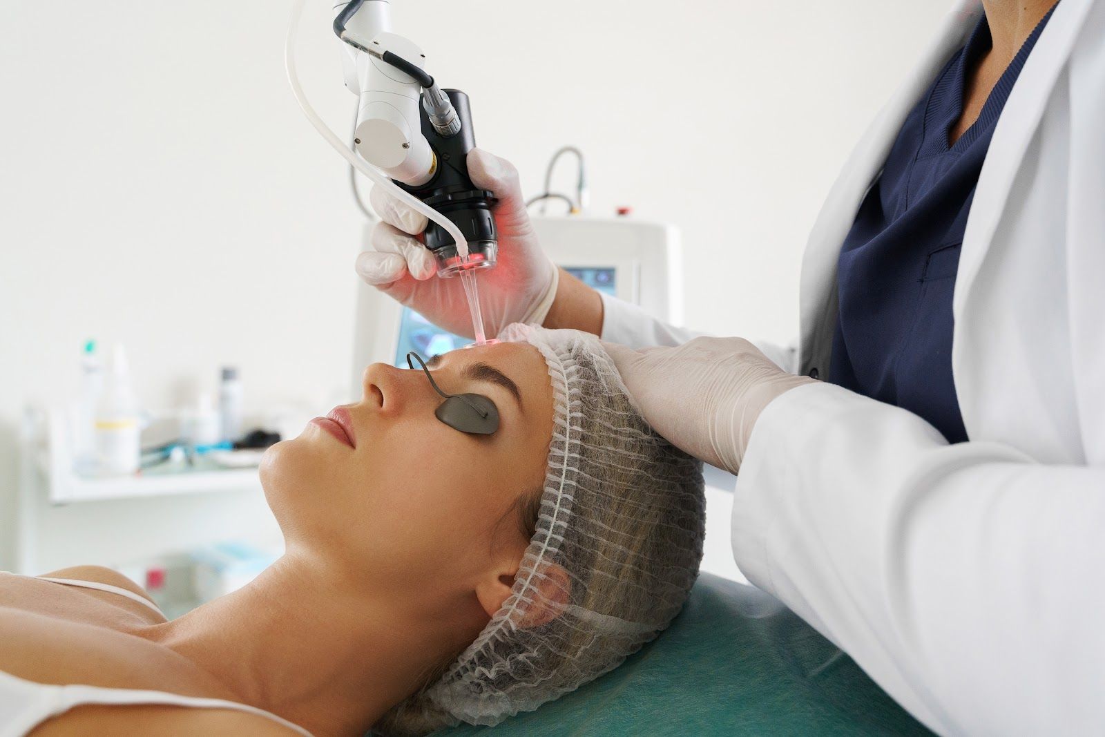 Cosmetic facial treatment with a masked practitioner using a device on a client’s face