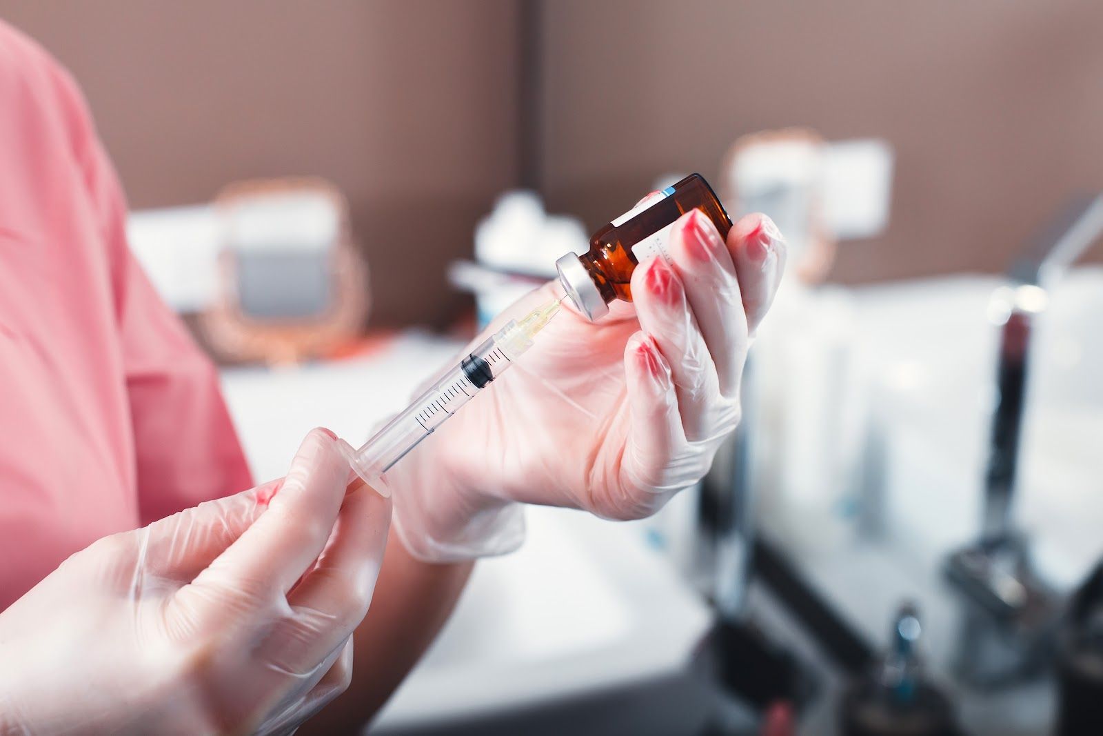 Gloved hands drawing liquid from a small vial with a syringe in a lab setting