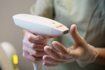 A woman is getting a laser hair removal treatment on her face.