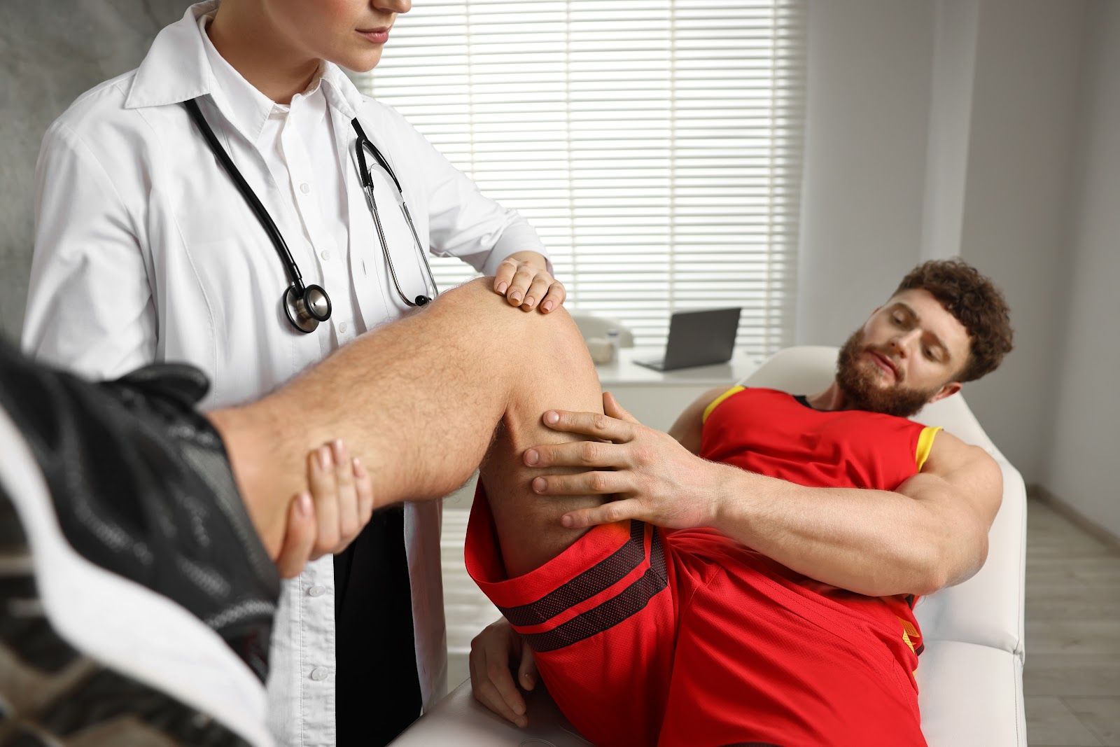 Doctor examining a patient’s injured leg in a bright clinic office