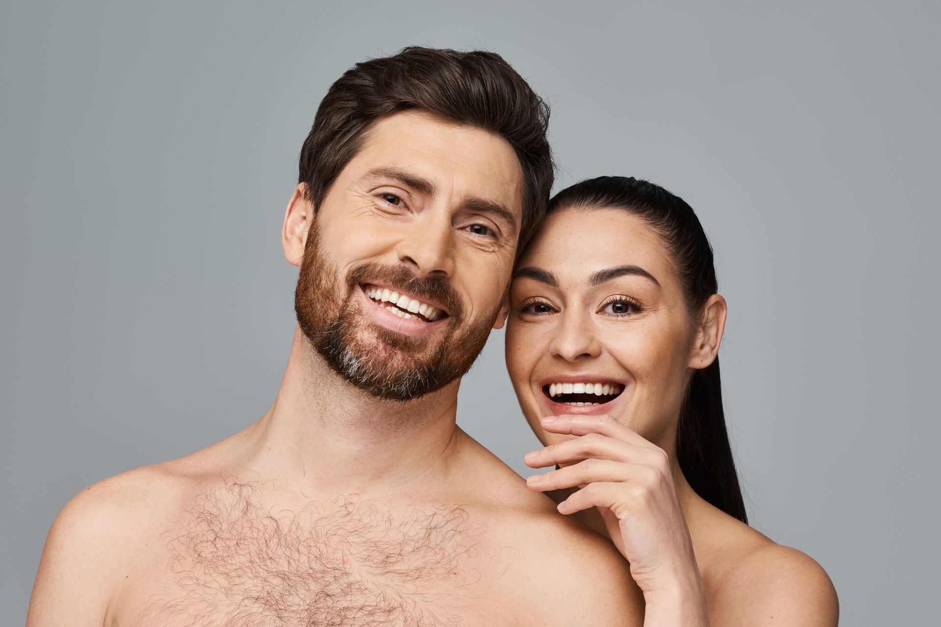 A shirtless man and a shirtless woman are smiling for the camera.