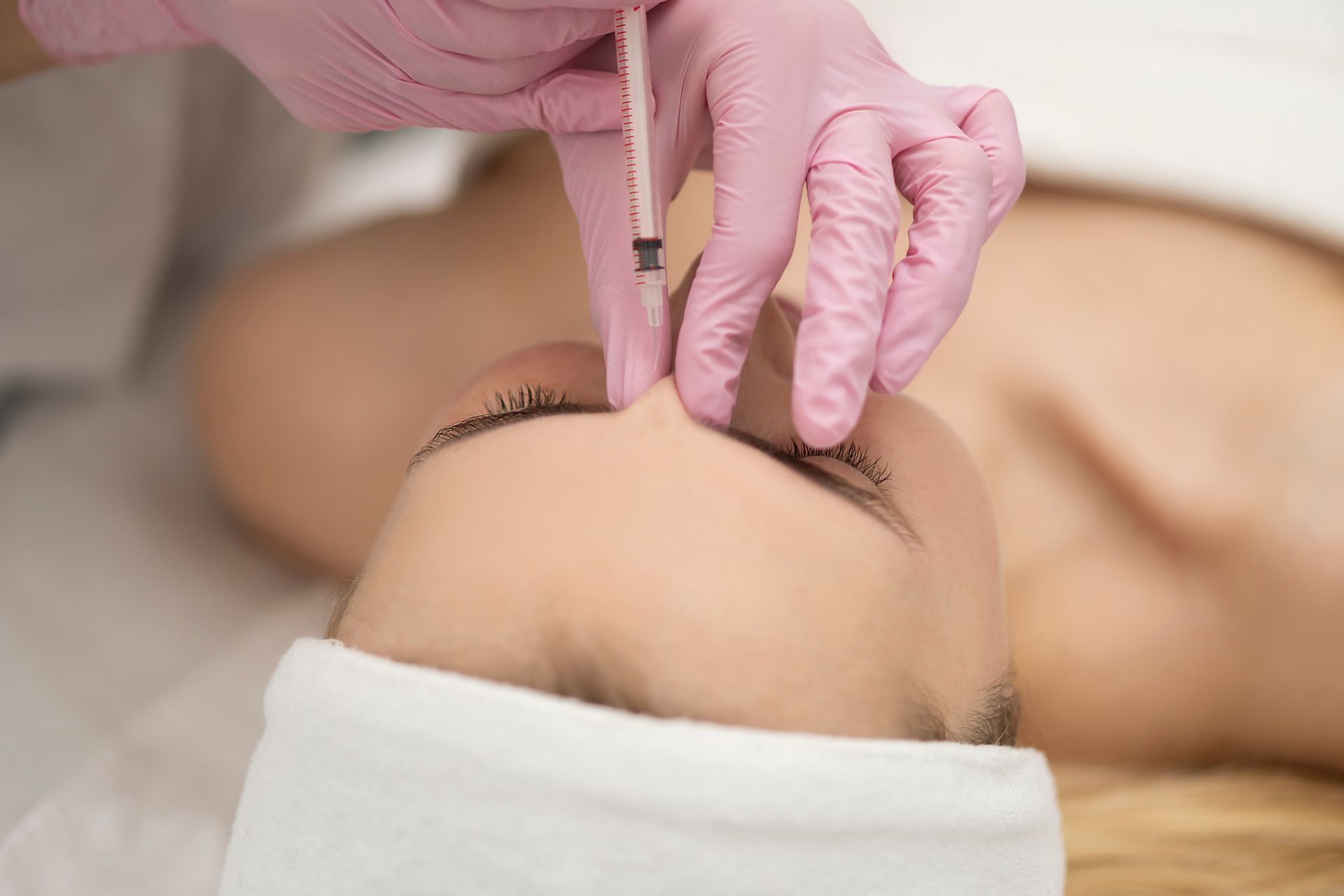 A woman is getting a botox injection in her forehead.
