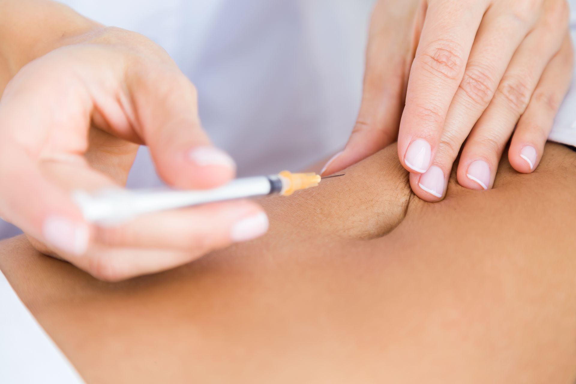 A woman is getting an injection in her stomach.