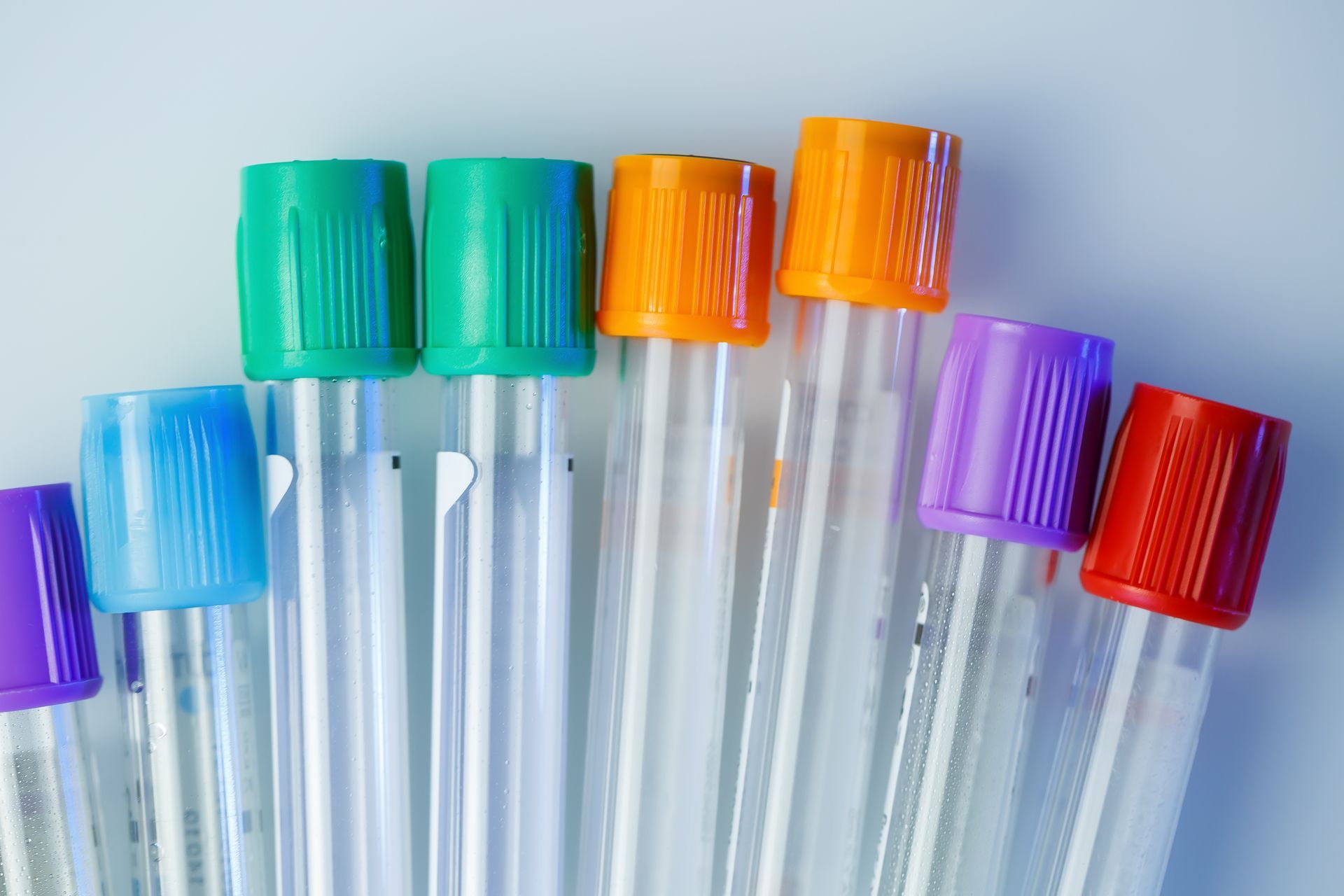 A bunch of test tubes with different colored caps are lined up in a row.