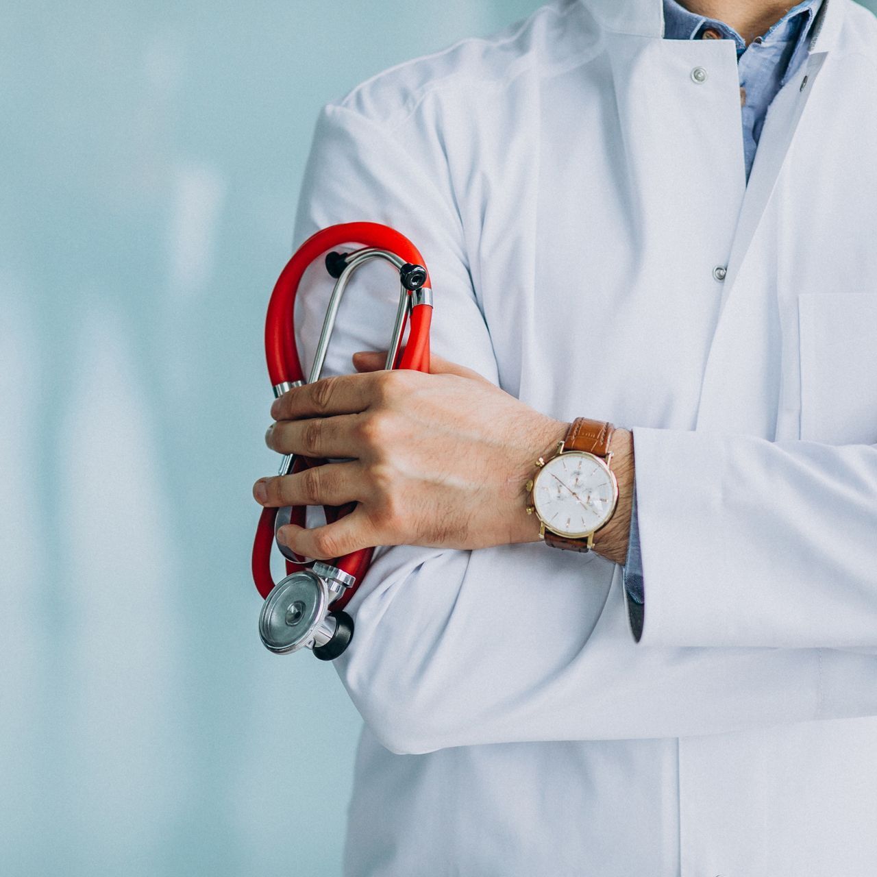 A doctor is wearing a watch and holding a stethoscope