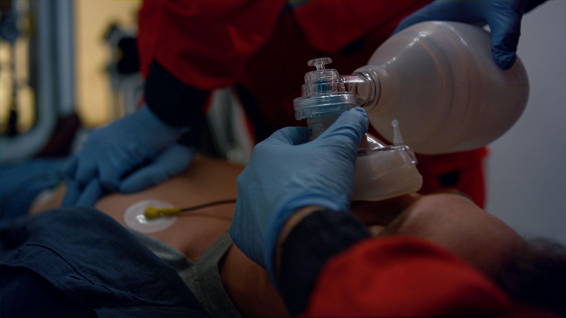 A person is laying in an ambulance with an oxygen mask on their face.