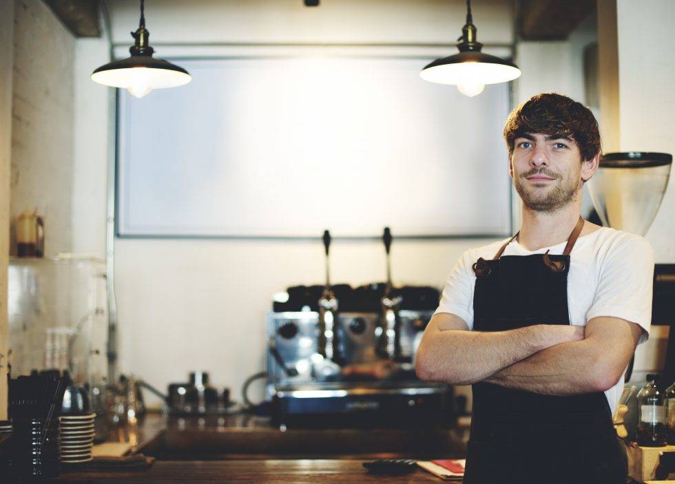 a man in an apron is standing in a kitchen with his arms crossed