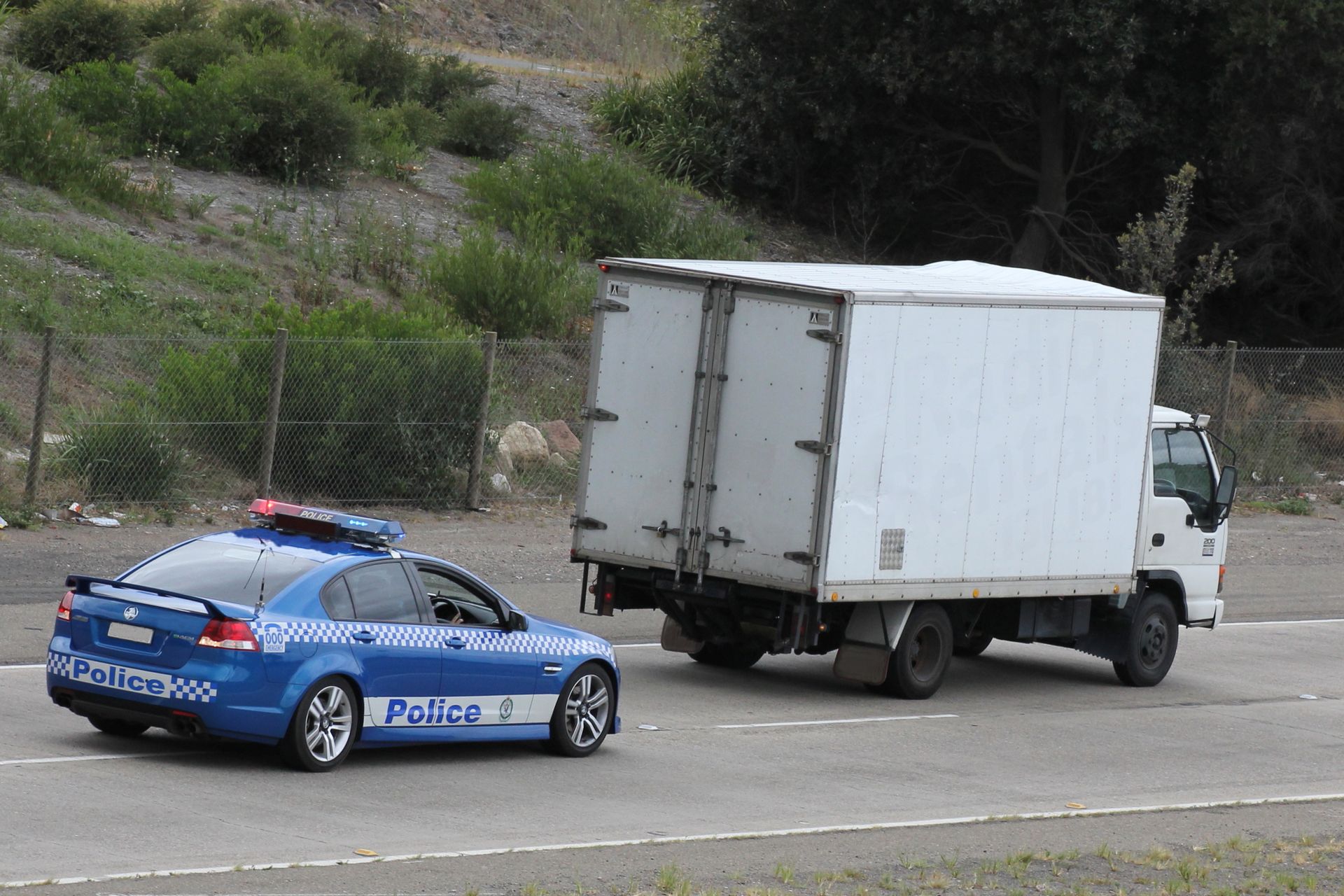 A white truck is being towed by a blue police car