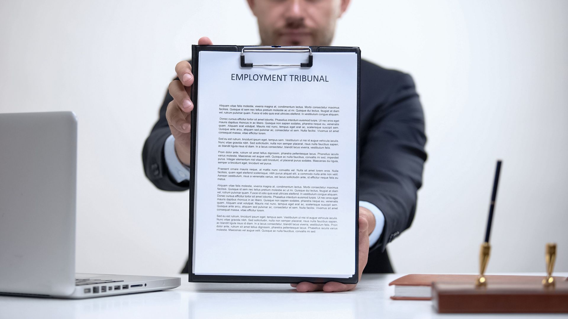A man in a suit is holding a clipboard with a piece of paper on it.