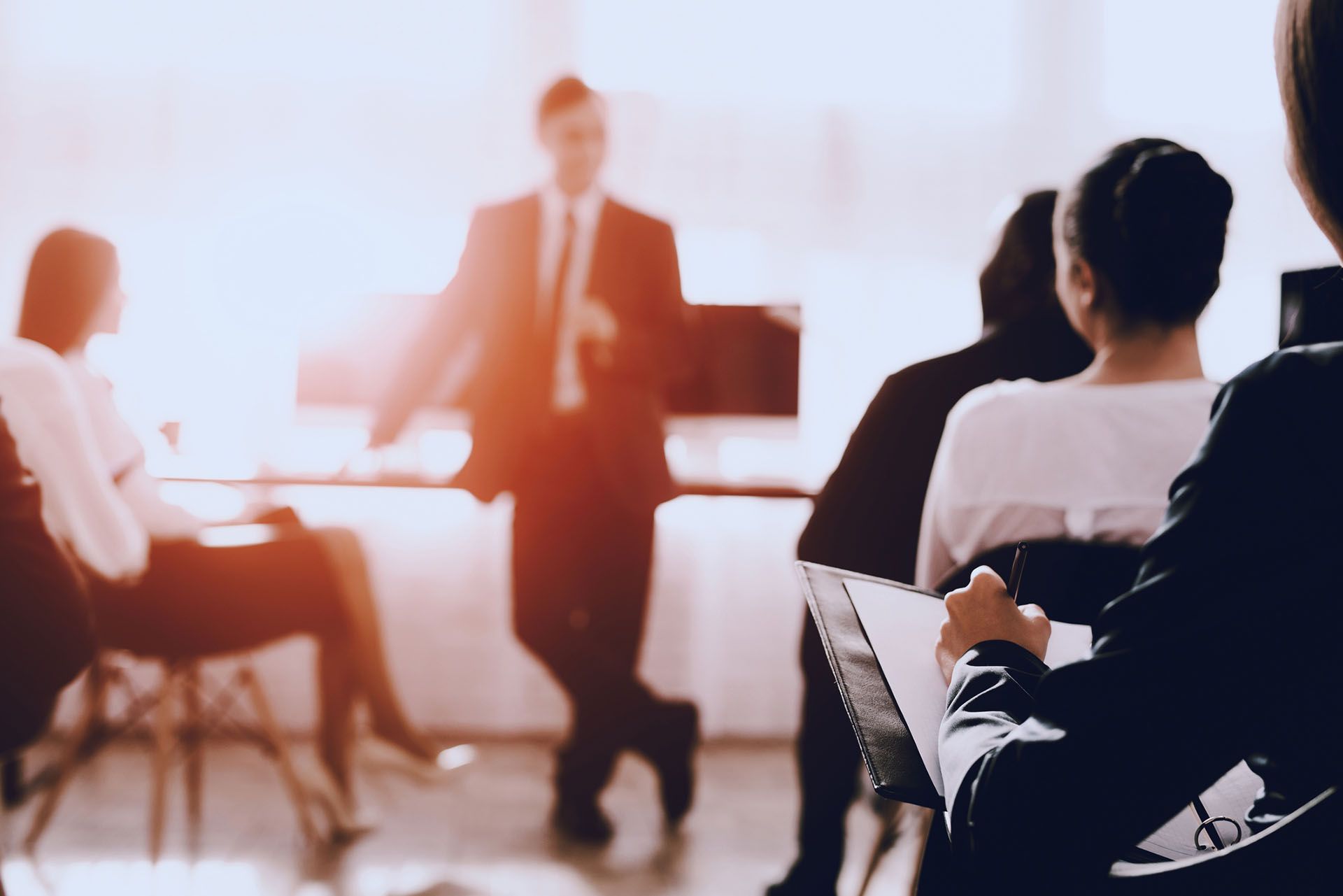 a man in a suit and tie is giving a presentation to a group of people sitting in chairs