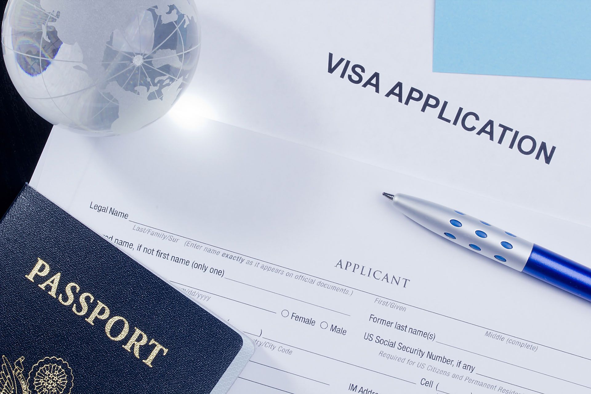 a passport and a pen are on top of a visa application