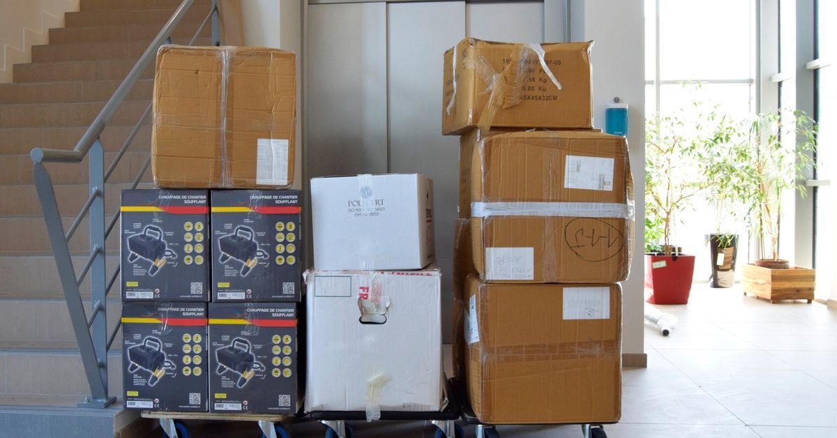 Several carts are placed next to an elevator and a stairwell. There are boxes on all the roller carts.