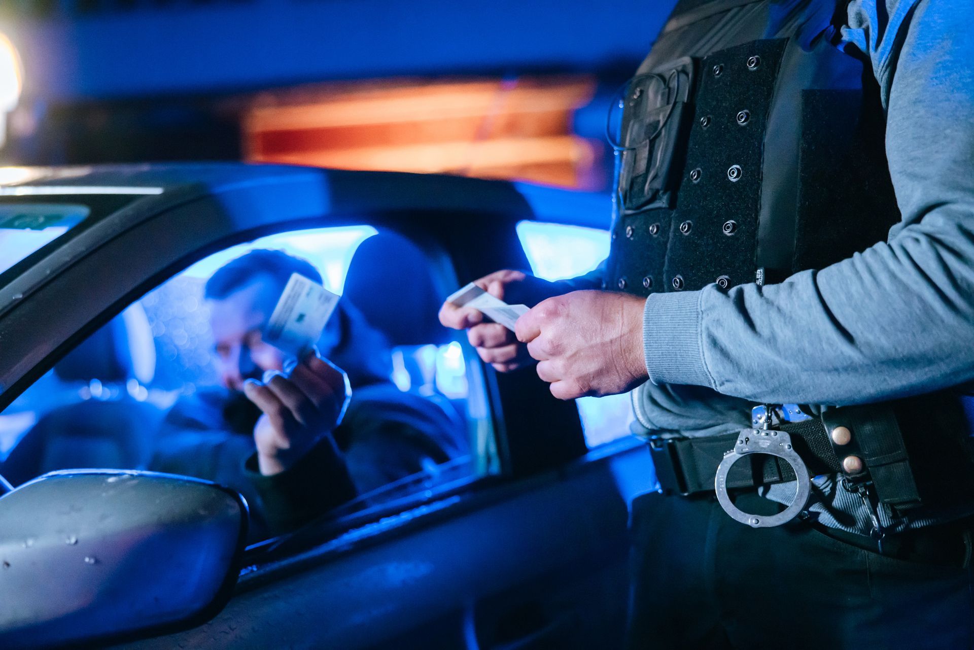 A police officer is handing a ticket to a man in a car.