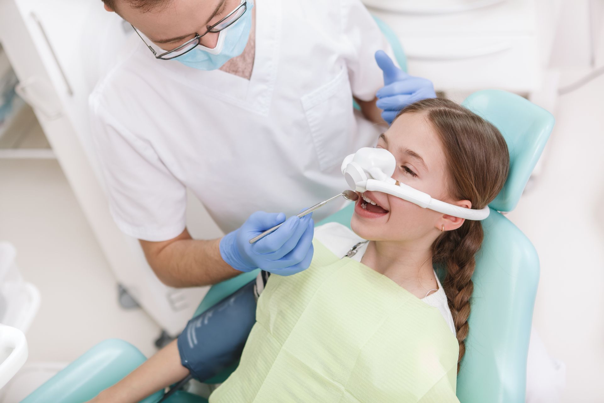 Young girl having her teeth treated while having inhalation sedation mask on.