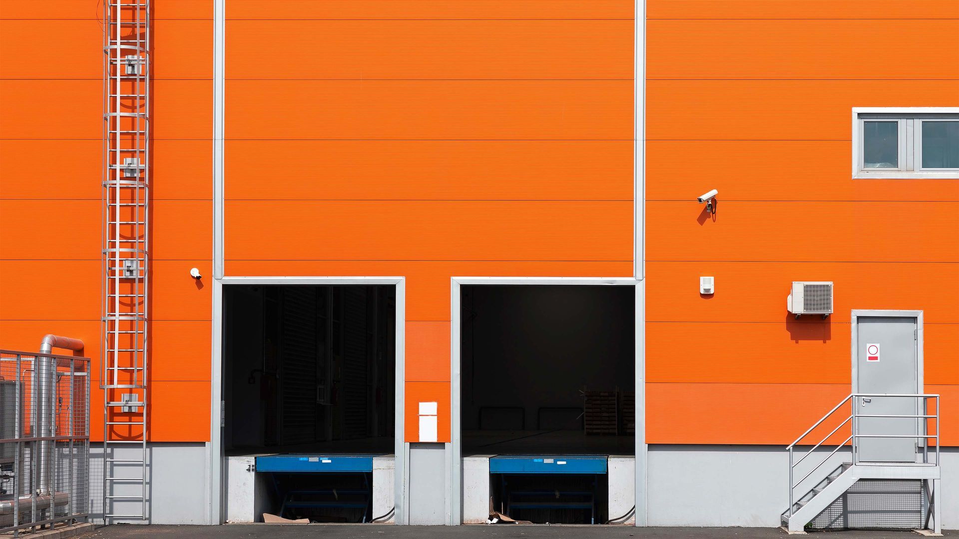 Industrial warehouse exterior with bright orange metal siding and loading dock doors