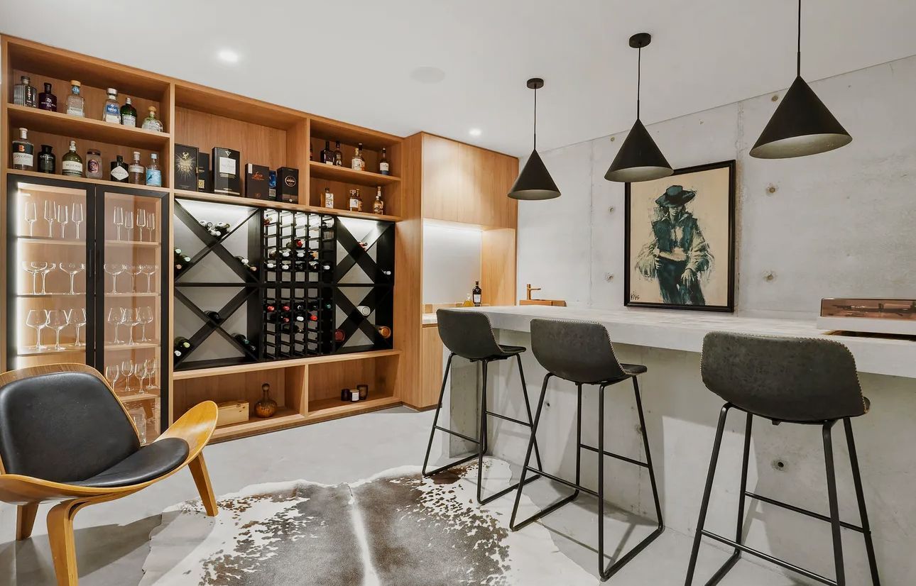 Wine bar with wooden shelving, a counter, stools, and a cowhide rug — Maken Kitchens & Cabinets in Chinderah, NSW