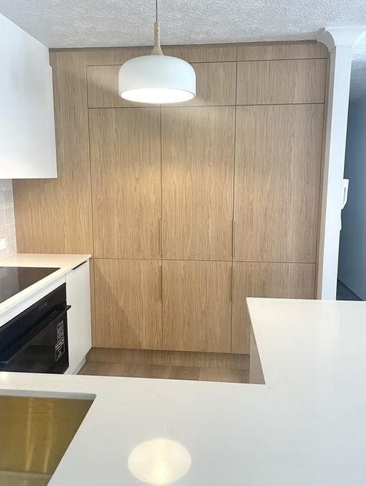 Modern kitchen with white cabinets, light wood floors, and a hanging plant.