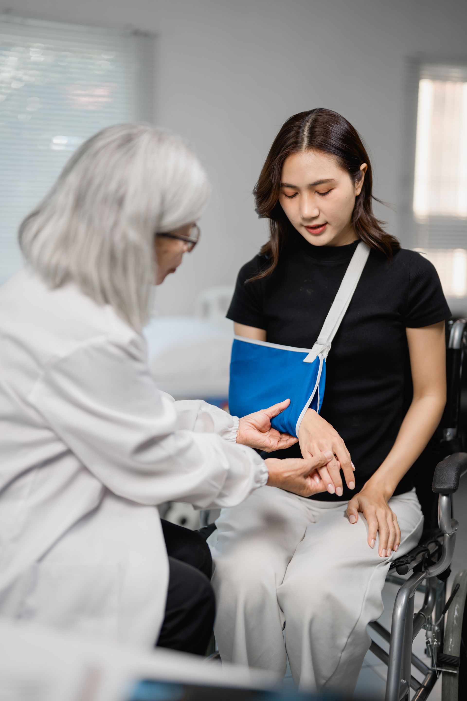 Doctor examining patient's injured arm in arm sling.