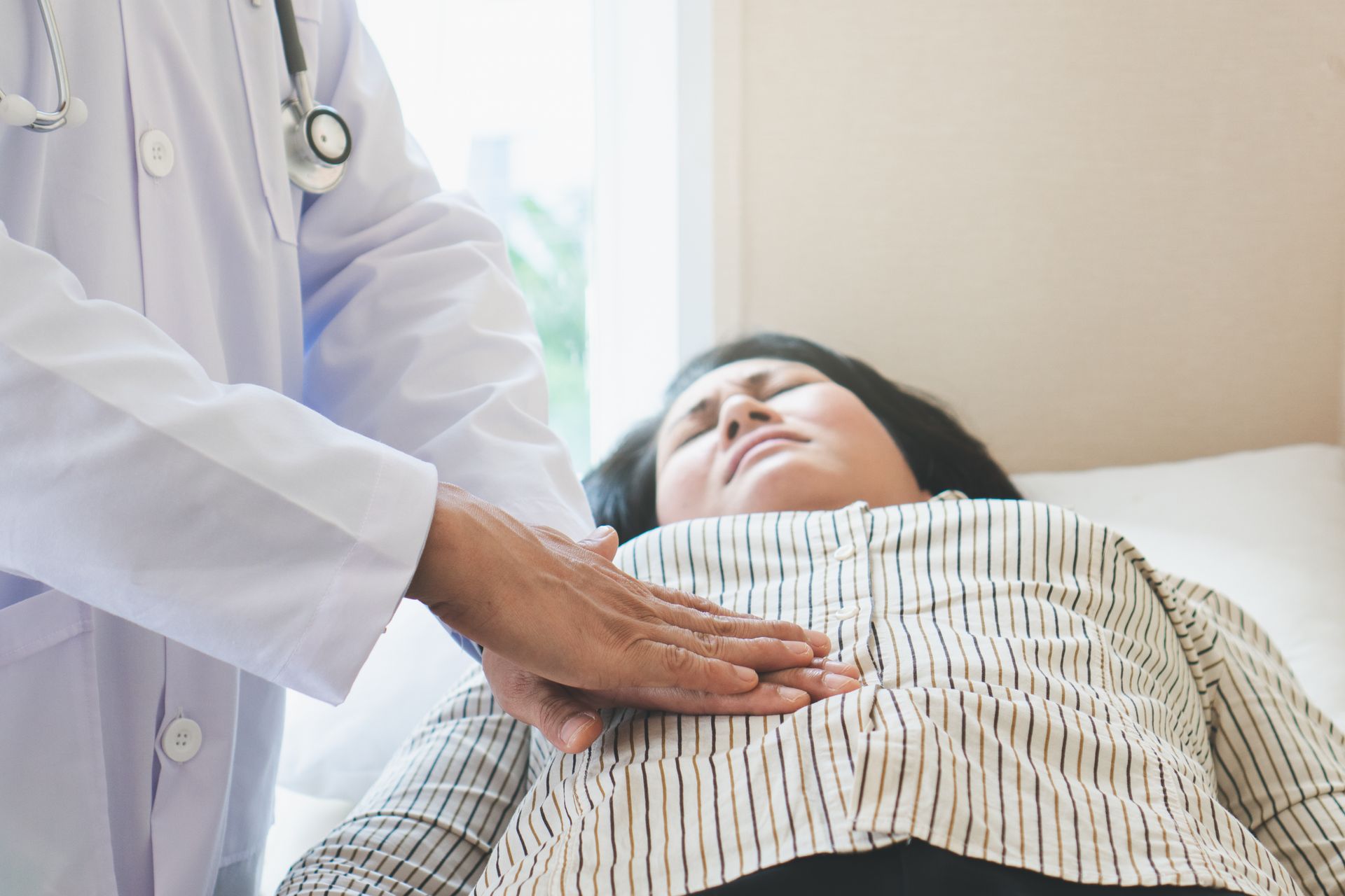 A doctor is examining the stomach of a woman.