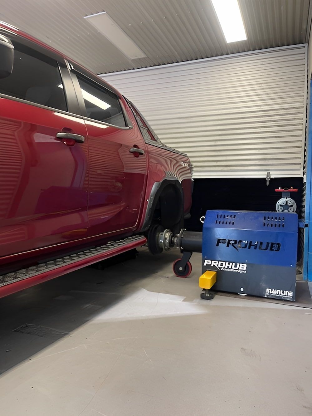 A Red Truck Is Parked In A Garage Next To A Machine — Hunter Automotive In Bungalow, QLD