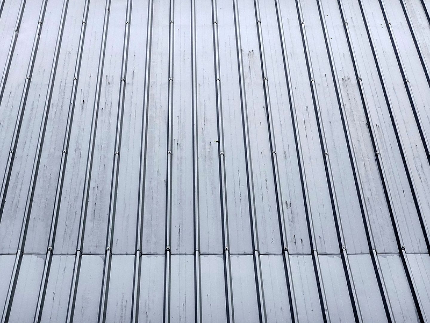 Vertical metal siding with thin dark seams and a blue-gray tint