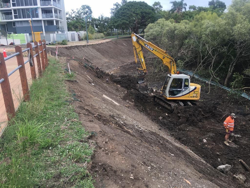 Excavator and Worker on a Dirt Embankment, Near a Building and Trees — CJD Investments (NQ) Pty Ltd in Mackay Harbour, QLD