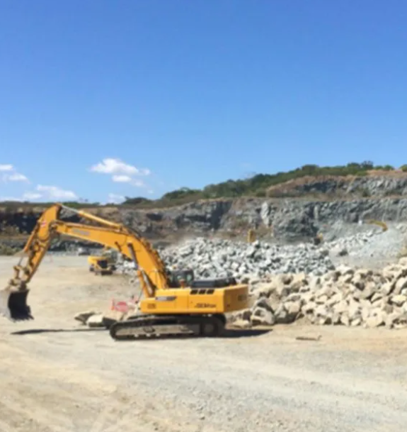 Yellow Excavator in a Quarry, Moving Rocks Under a Clear Blue Sky — CJD Investments (NQ) Pty Ltd in Mackay Harbour, QLD
