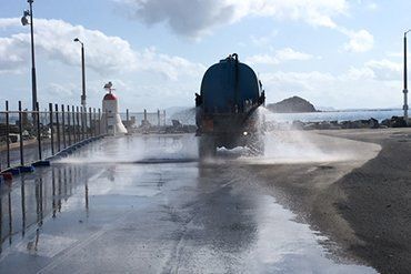 A Water Truck Sprays a Wet Road Near a Coast on a Sunny Day — CJD Investments (NQ) Pty Ltd in Mackay Harbour, QLD