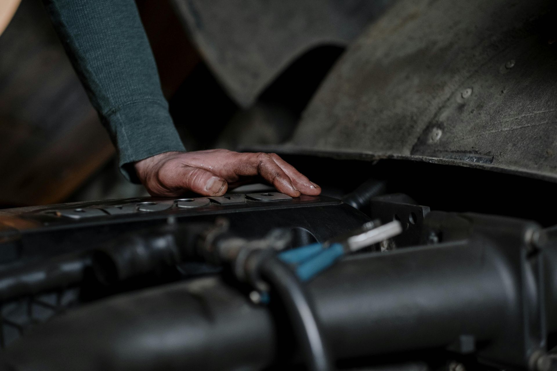 A person is working on a car engine with a laptop. | Jack Jr’s Auto Repair