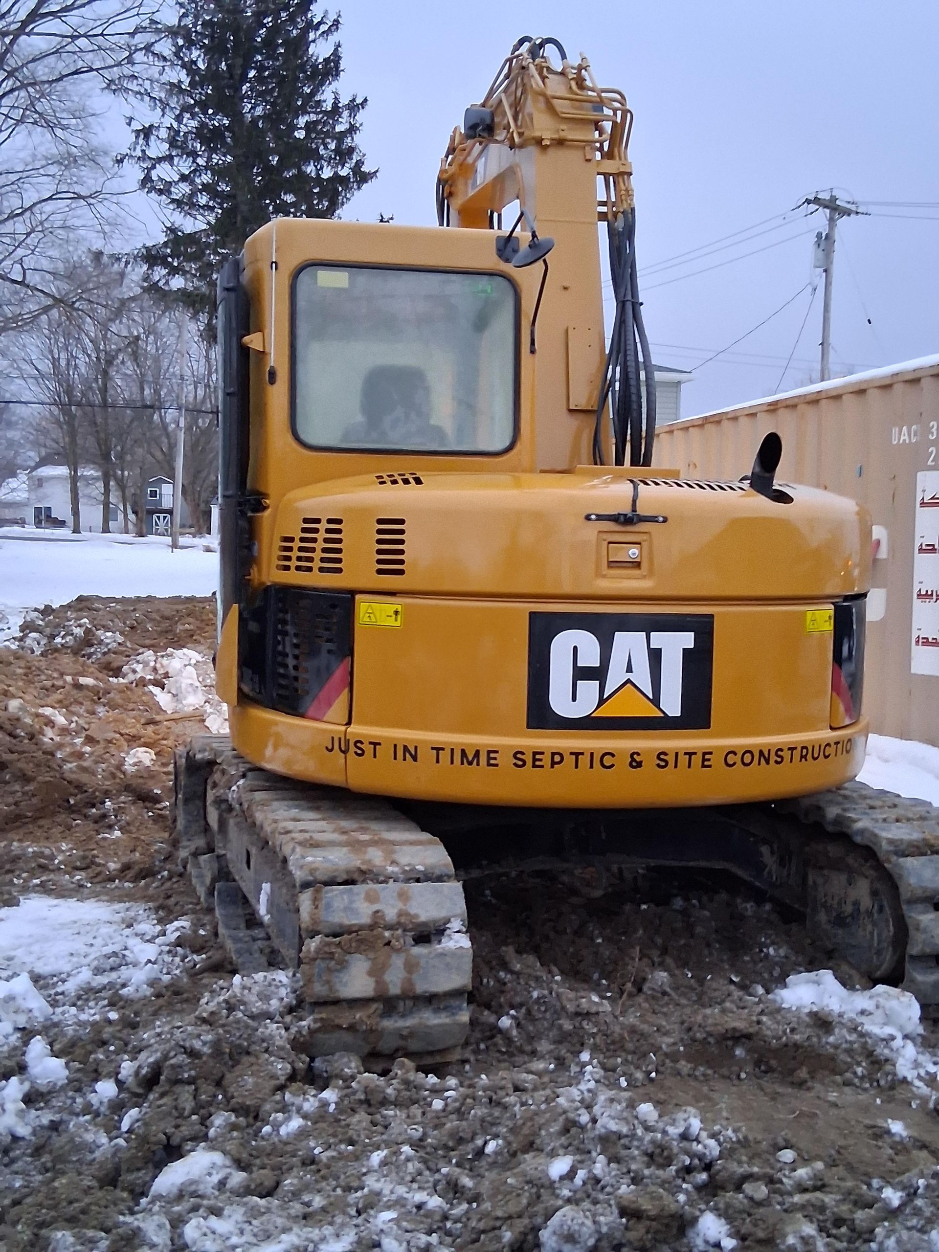 A yellow cat excavator is parked in the snow