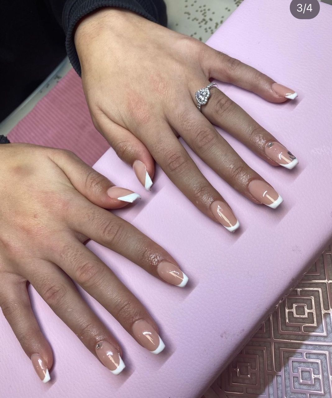 De handen van een vrouw met een french manicure en een ring aan haar vinger