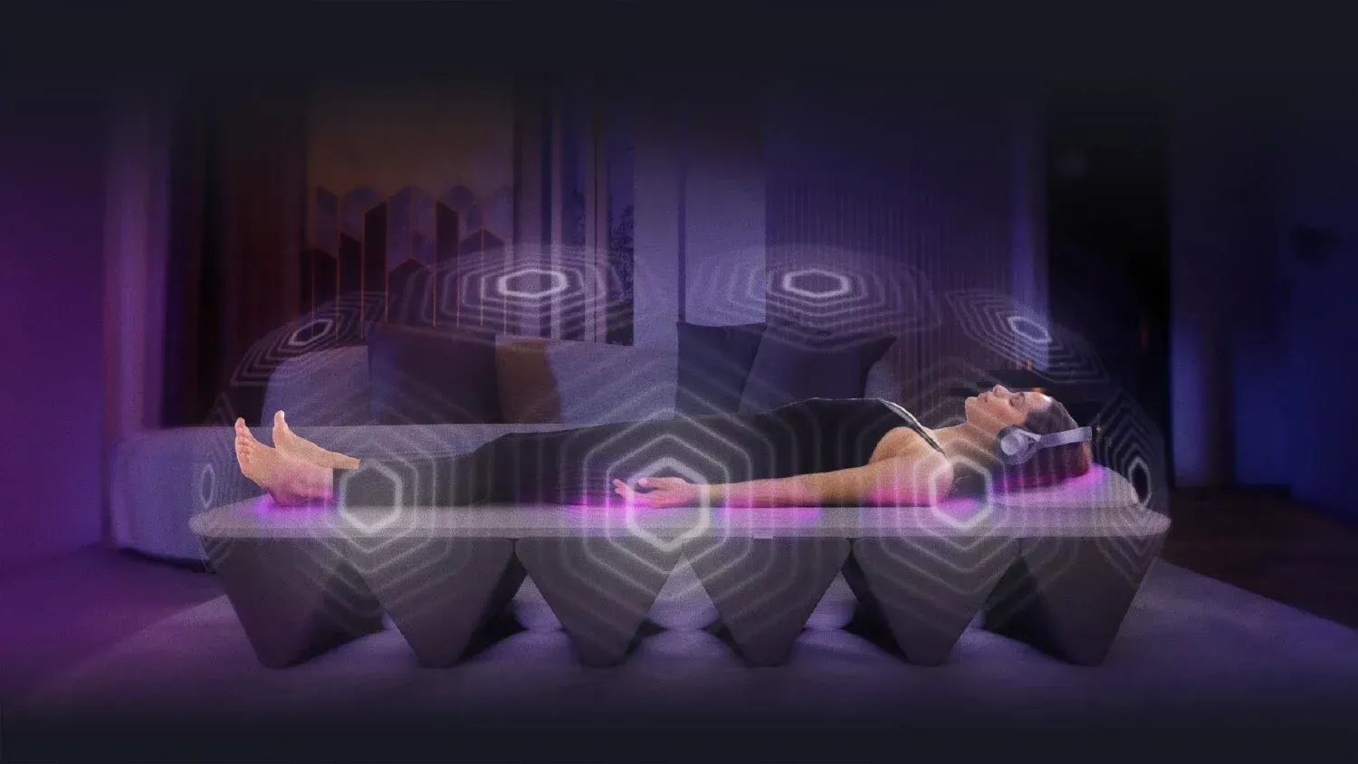 A woman is laying on a couch wearing headphones.