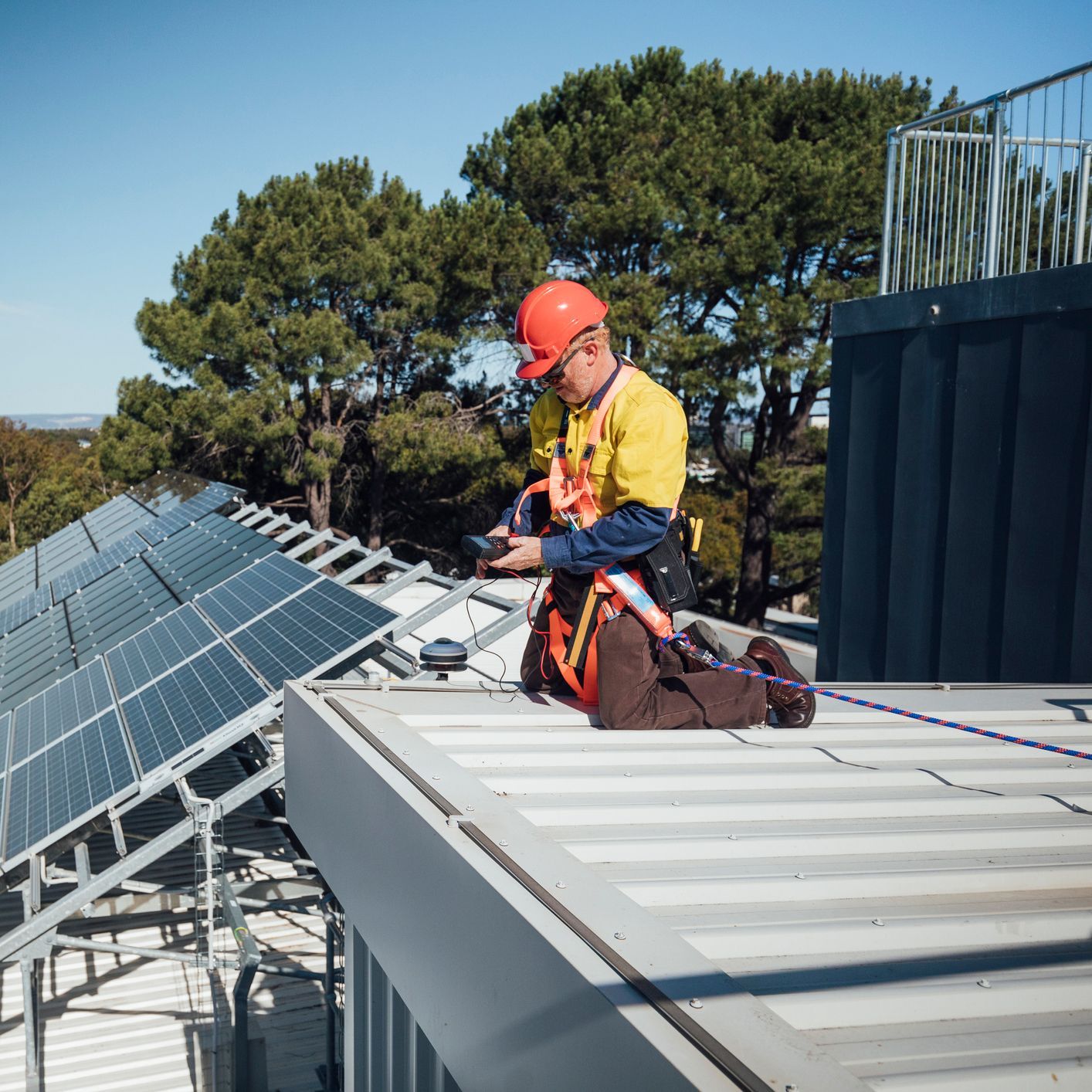 A man is working on the roof of a building with solar panels.