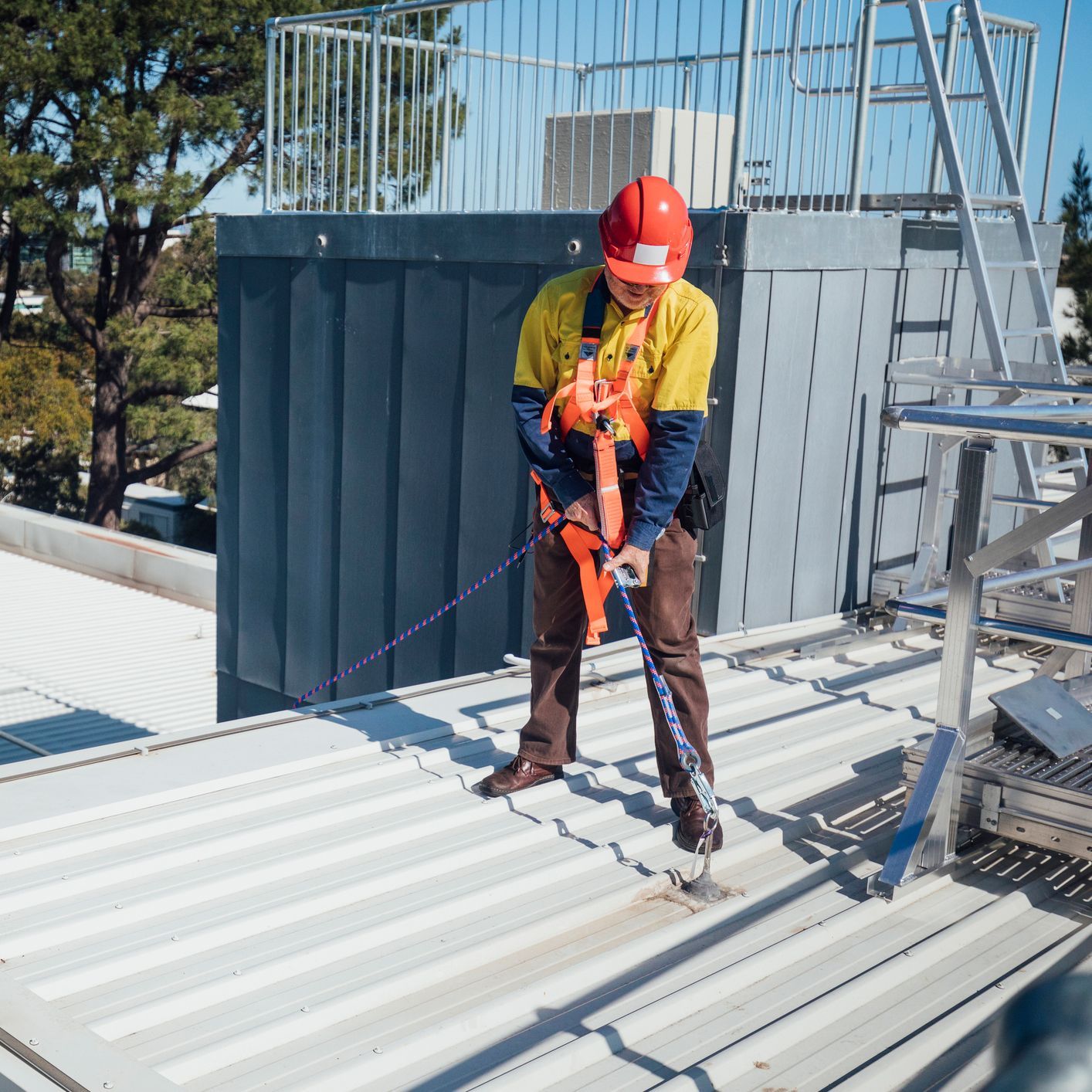 A man wearing a hard hat is working on a roof