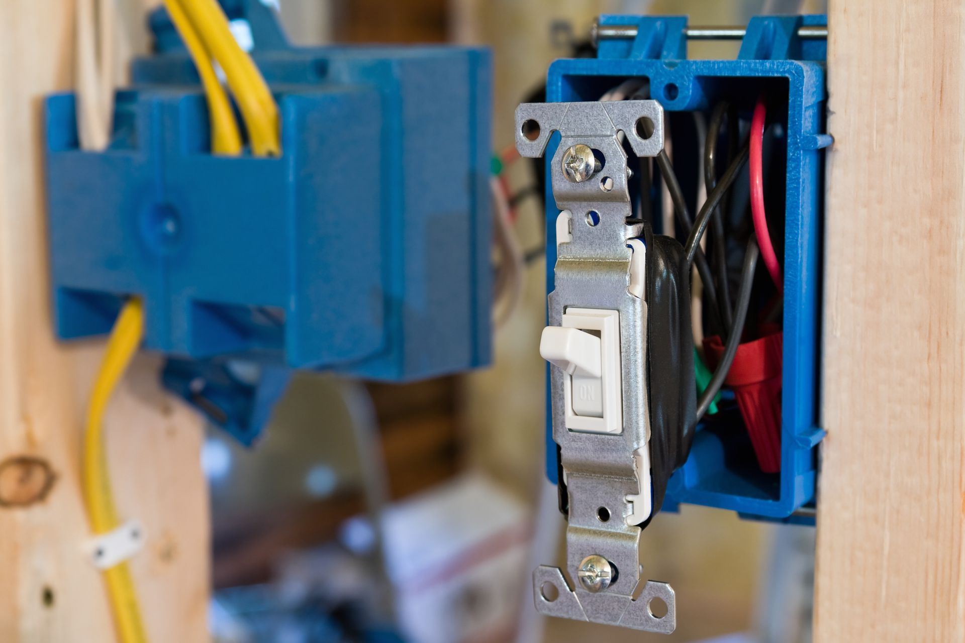 A light switch is being installed in a blue box on a wooden wall.