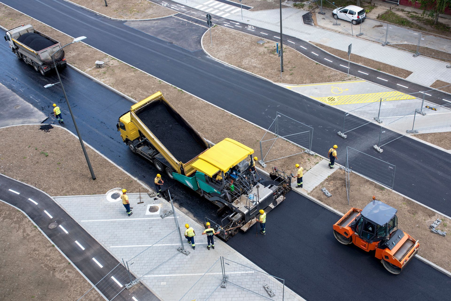 Aerial view of road paving crew resurfacing a street with asphalt machinery.