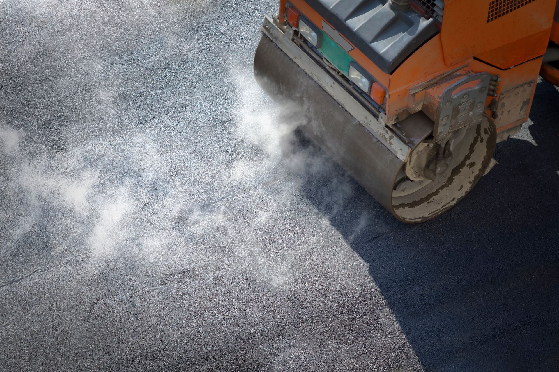 A machine steam rolling new and hot asphalt, showcasing commercial asphalt paving services.