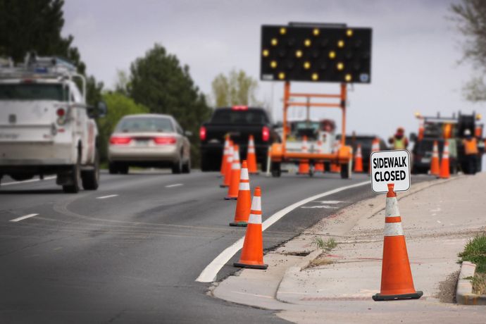 Roadwork lane closure with orange cones, road sign, and traffic on a city street Roadwork lane closure with orange cones, road sign, and traffic on a city street