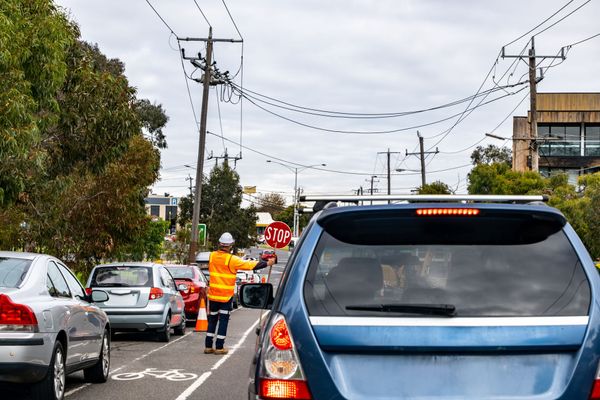 Traffic jam on a city street with a road worker in orange directing cars near a blue SUV Traffic jam on a city street with a road worker in orange directing cars near a blue SUV