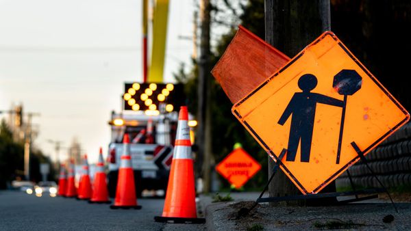Orange roadwork warning signs and traffic cones lining a street with a blurred barrier in the background Orange roadwork warning signs and traffic cones lining a street with a blurred barrier in the background