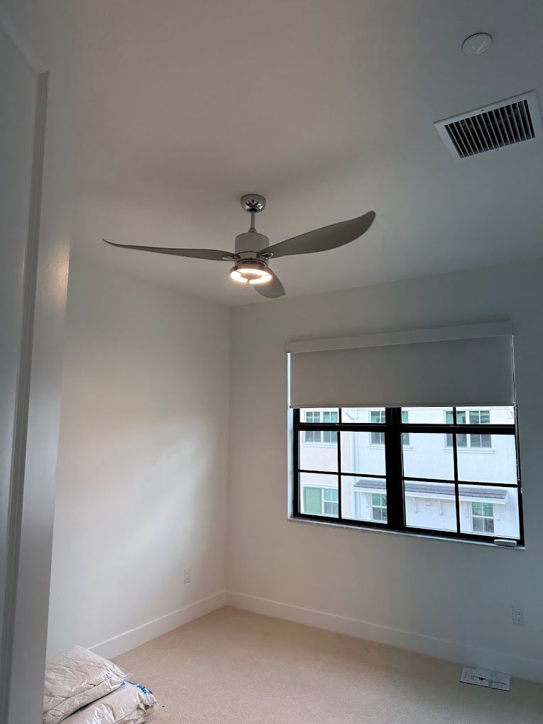 A bedroom with a ceiling fan and a window.