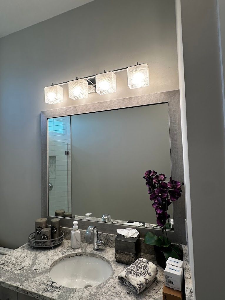 A bathroom with a sink , mirror and light fixture.