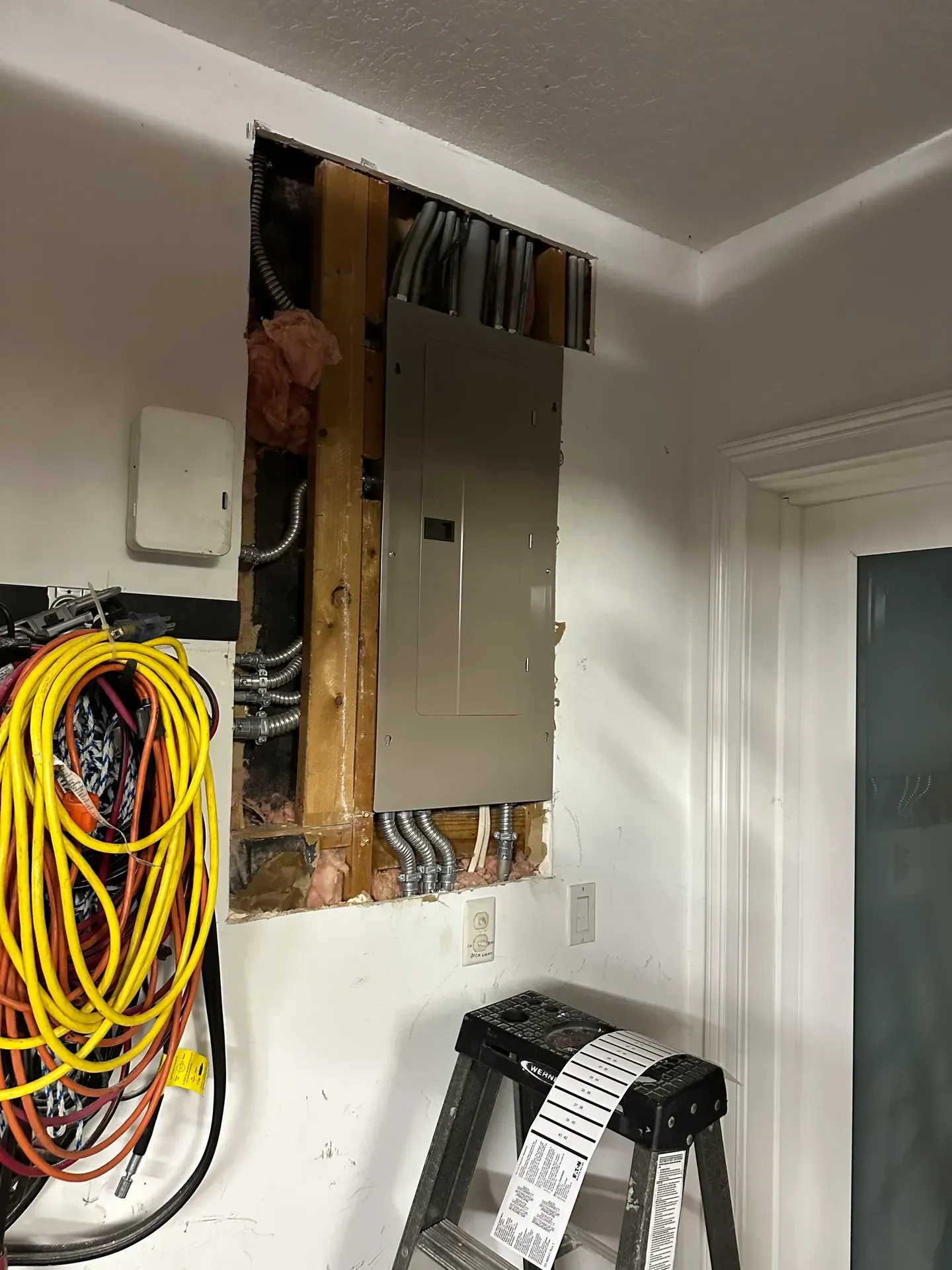 A ladder is sitting in a room next to a wall with a box on it.