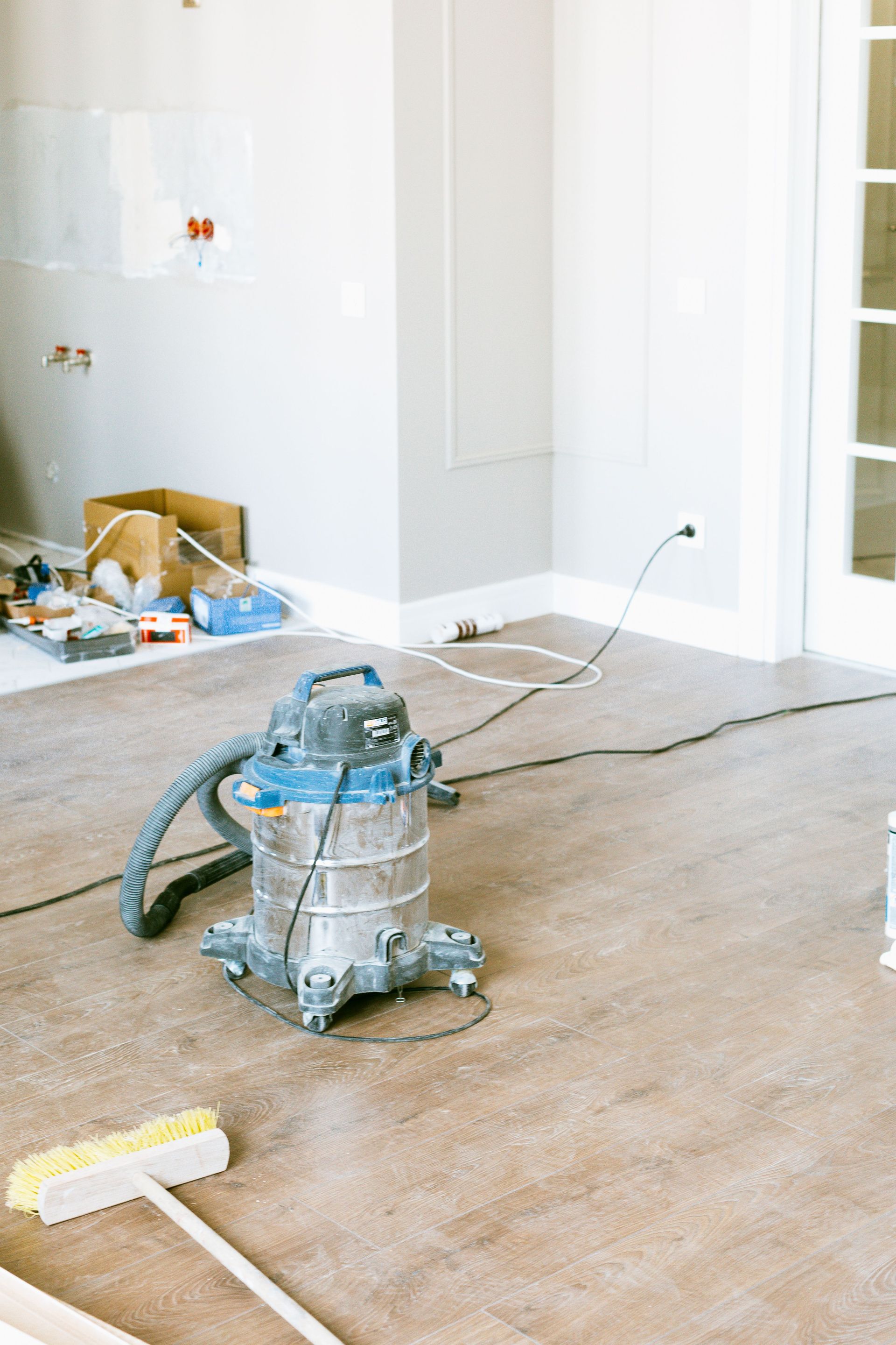 A low-angle view of a modern building facade featuring wood siding and grey panels with large, dark-framed glass windows.