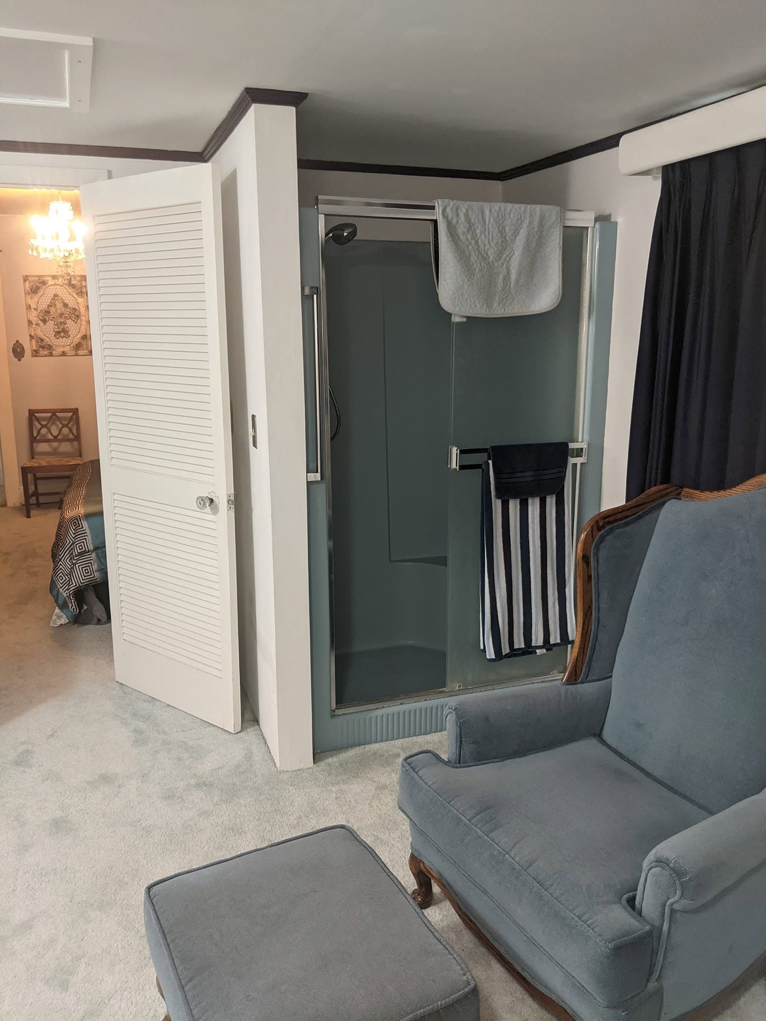 Small room with an open white door, gray exercise machine, and blue armchair on carpet.