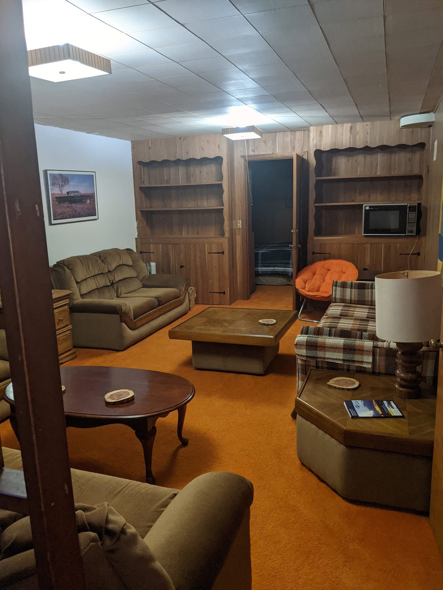 Retro living room with brown couches, wood paneling, coffee tables, and a TV